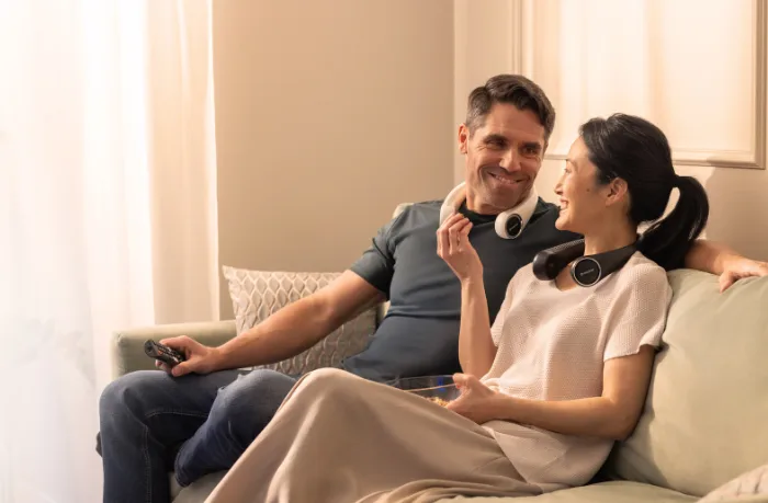 Couple relaxing at home with portable neck fans for quiet cooling