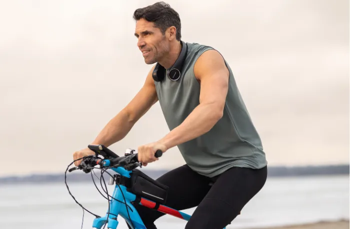 Man wearing the Respiray Neck Fan while cycling near the coast